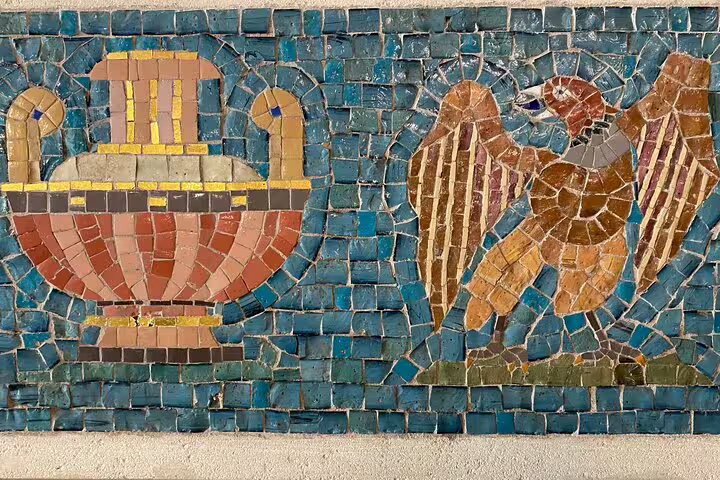Ancient mosaic tile artwork depicting a decorative urn and eagle on turquoise background