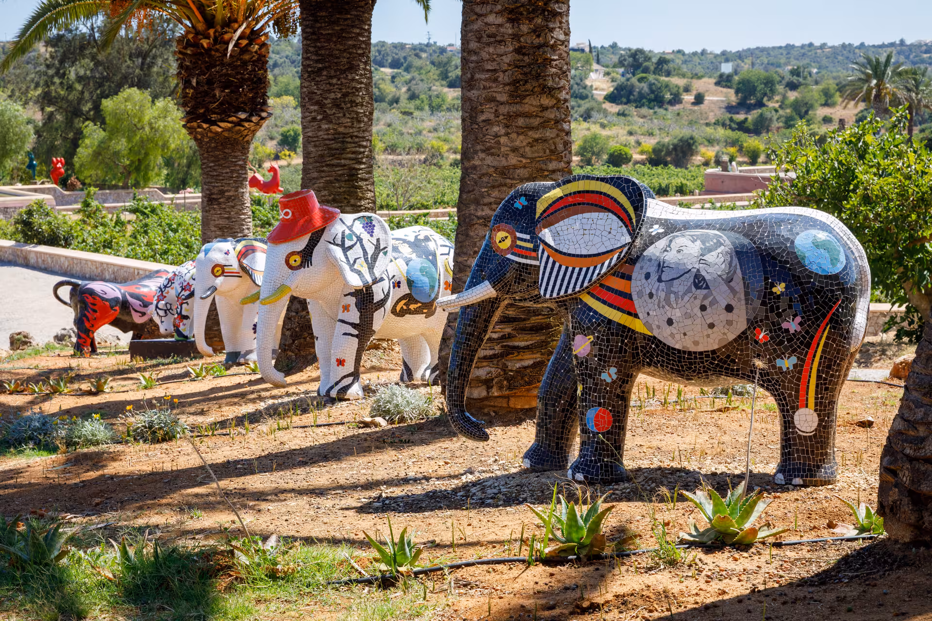Colorful mosaic elephant sculptures in a sunny vineyard garden during a free-flow wine tasting guided tour