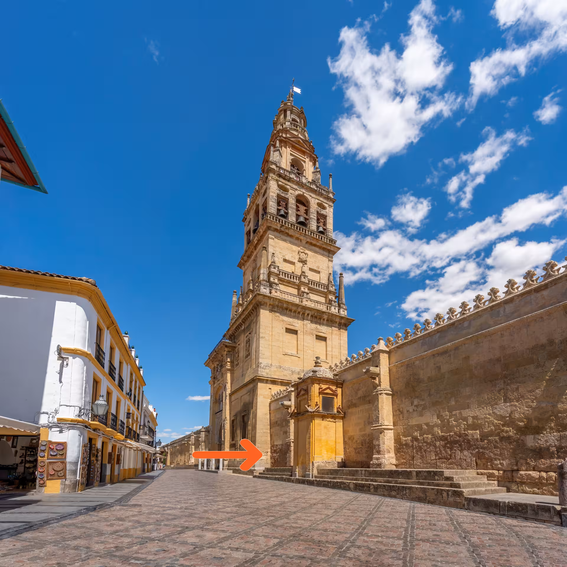 Exterior view of the iconic bell tower of the Mosque-Cathedral in Córdoba under a clear blue sky.