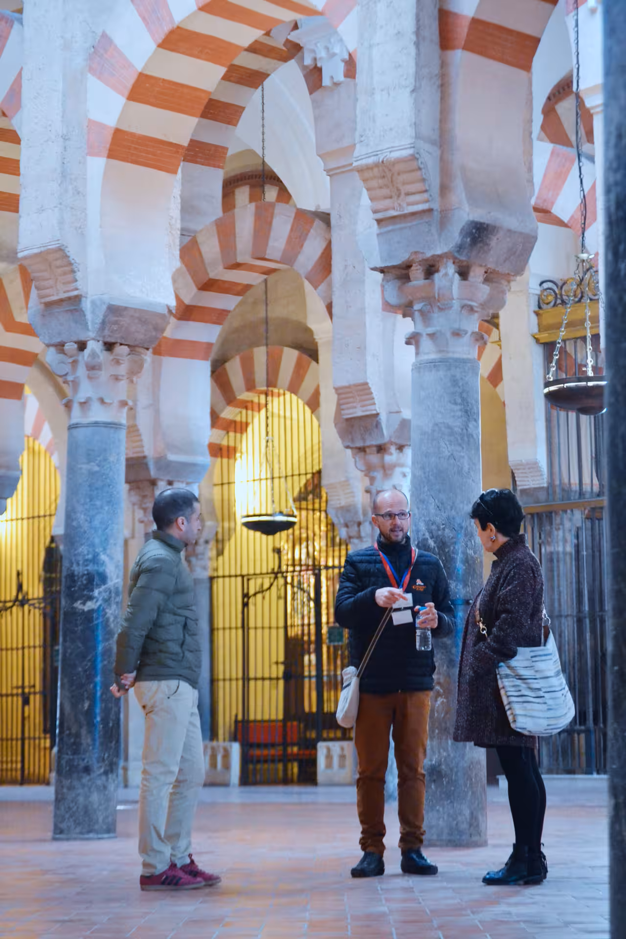 Tour guide explaining the intricate arches inside the historic Mosque-Cathedral of Córdoba to visitors.