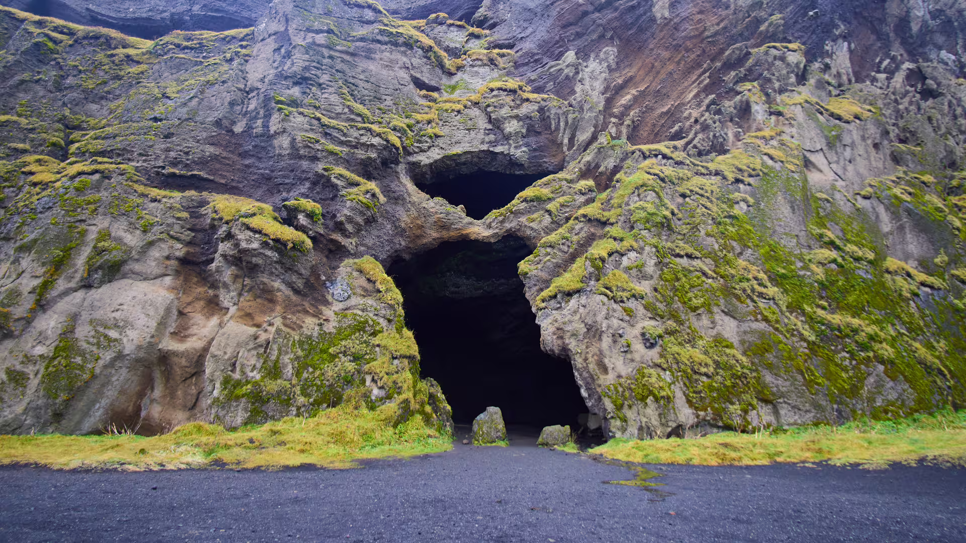 Moss-covered Viking cave entrance with black sand floor on Southeast Iceland Viking Journey tour