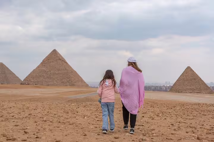 Mother and child walking toward the Giza Pyramids on a private day trip from El Sokhna Port to Cairo and GEM