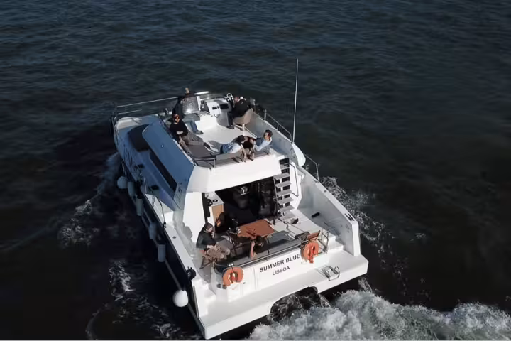 Aerial view of a motor catamaran in Lisbon, certified Clean & Safe, offering tours for up to 18 people.