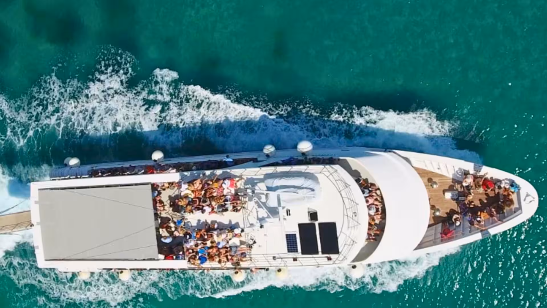 Aerial view of a motorboat full of tourists cruising the turquoise waters of the Aeolian Islands near Stromboli.
