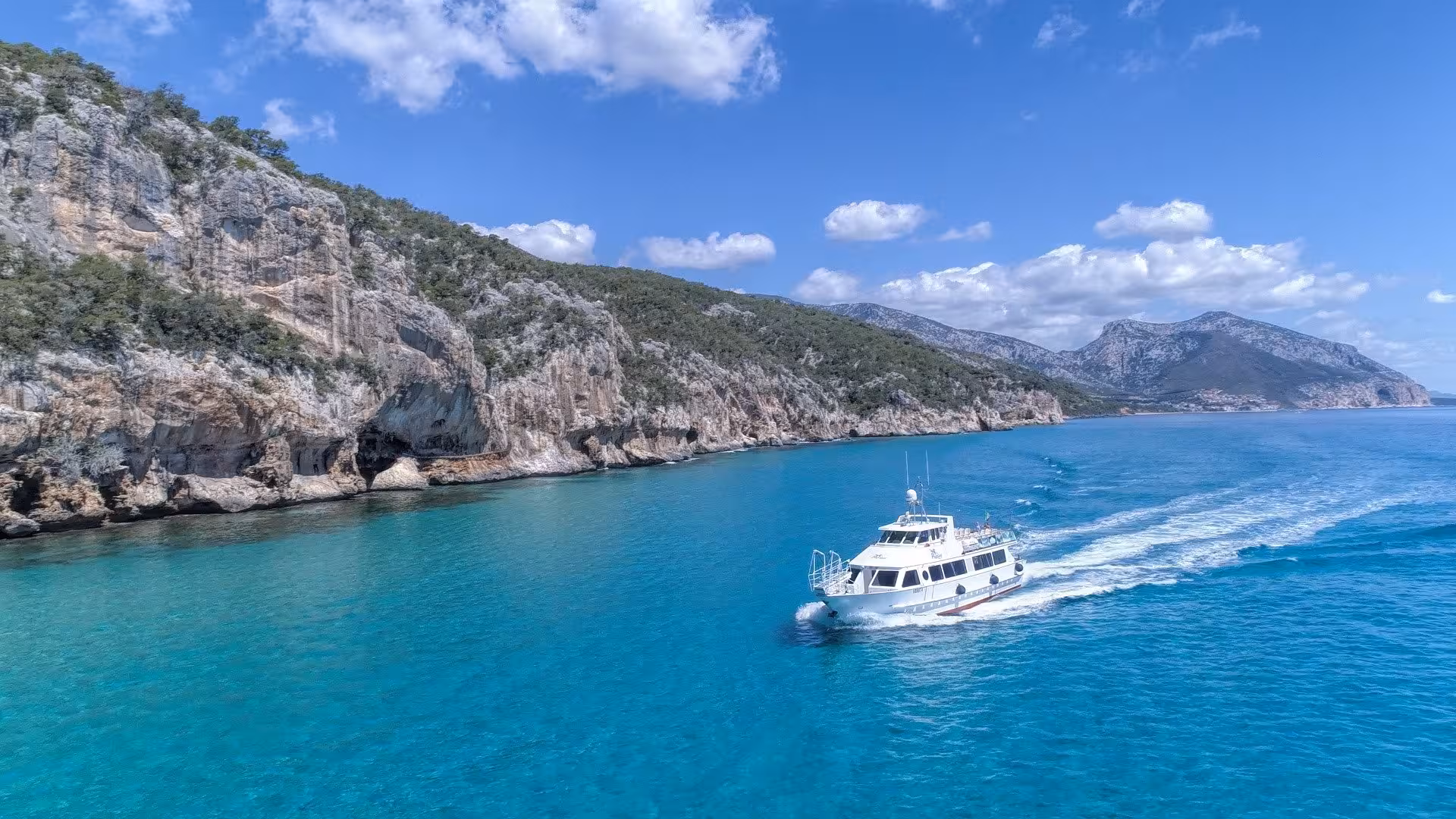 Motorboat cruising along Cala Gonone's rocky coastline with clear waters, en route to the Bue Marino Caves.