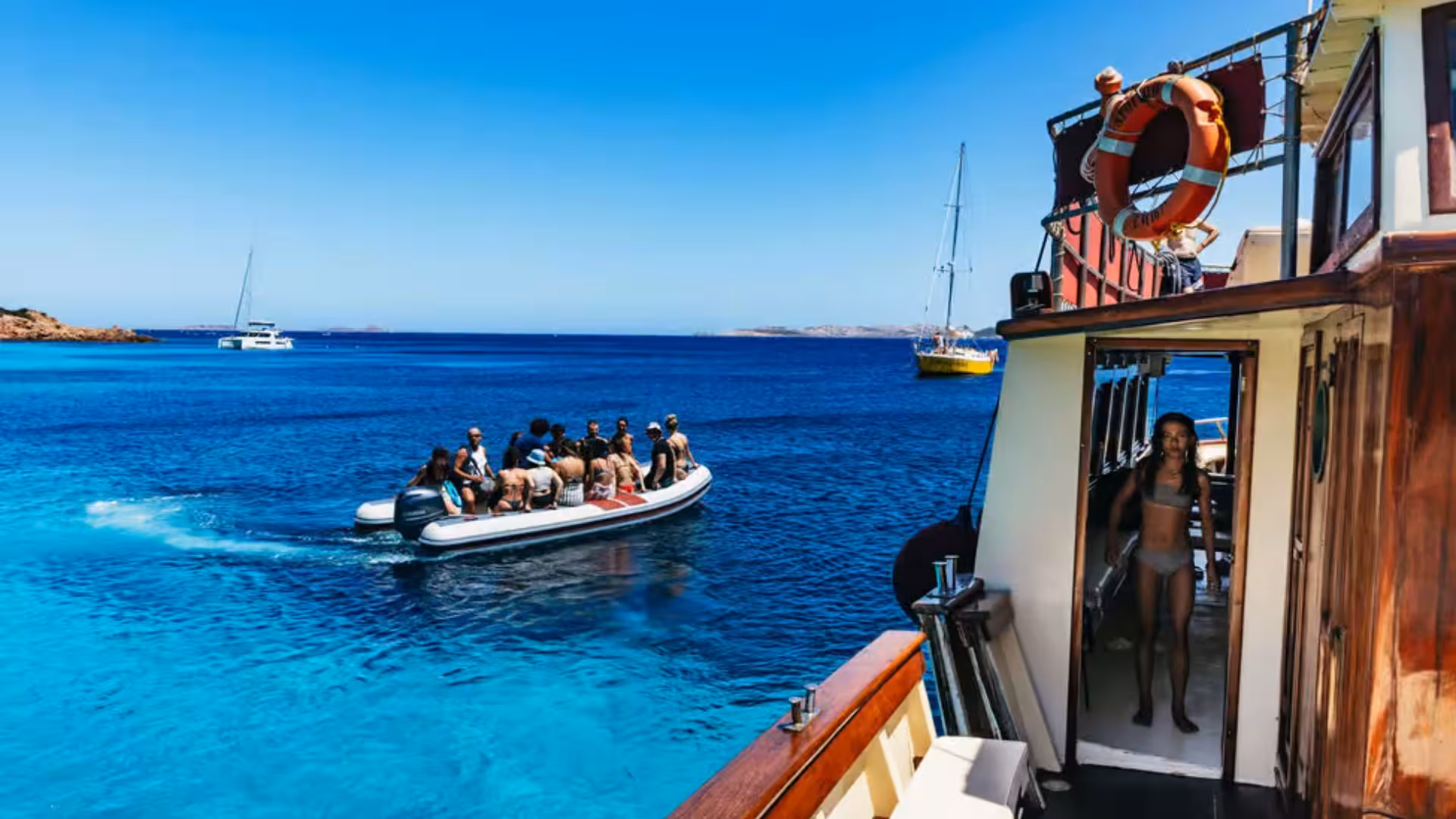 Tourists on a motorboat exploring the vibrant blue waters of La Maddalena Archipelago on a guided tour from Palau.