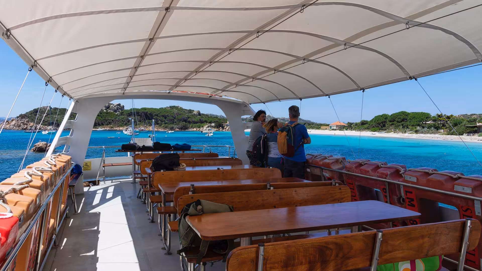 Tourists enjoying a motorboat ride with scenic views of La Maddalena Archipelago's turquoise waters and beaches.