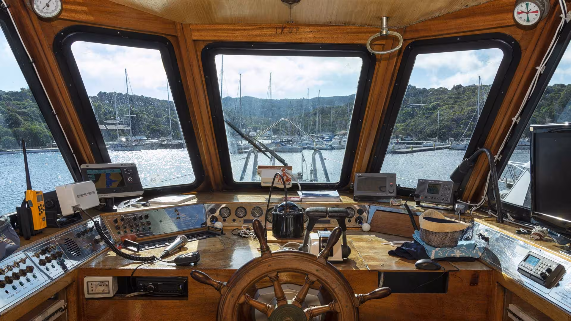 Interior view of motorboat's wheelhouse with navigation tools, offering scenic La Maddalena Archipelago tour experience.