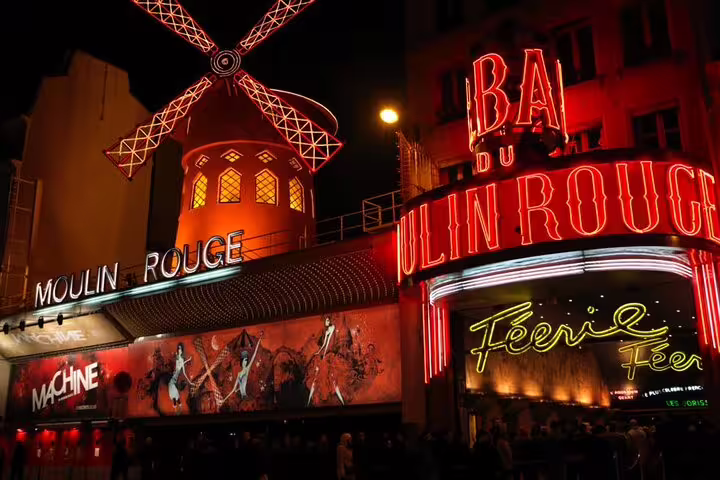 Moulin Rouge cabaret lit up with red neon signs at night in Montmartre, Paris