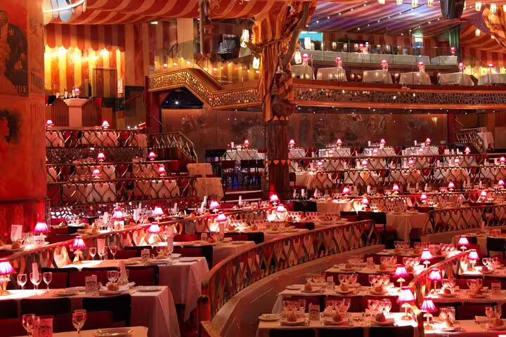 Moulin Rouge cabaret dining hall with pink lamp-lit tables and ornate red decor in Paris