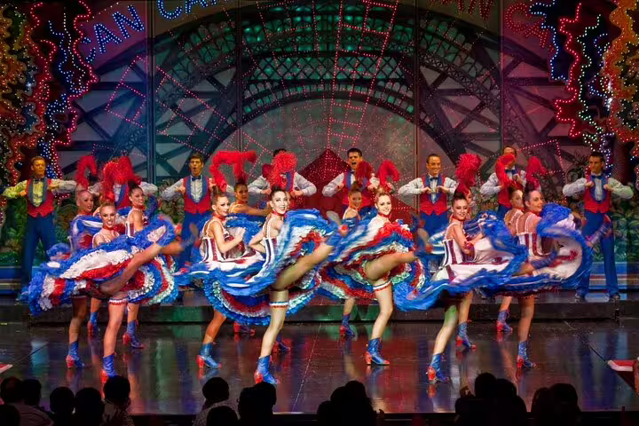 Can-Can dancers in colorful blue and red costumes performing on stage at Moulin Rouge Paris