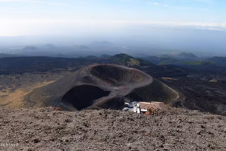 Aerial view of Mount Etna's volcanic craters showcasing rugged terrain under a clear blue sky.