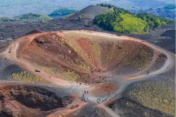 Hikers exploring colorful volcanic craters and lava fields on Mount Etna during a private day trip from Cefalù