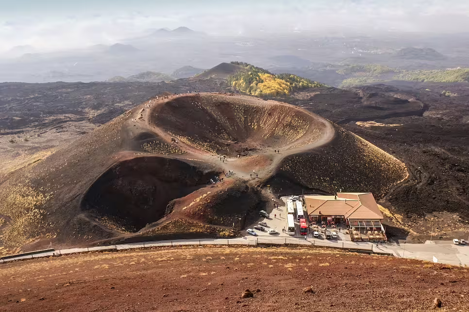 Panoramic view of Mount Etna volcanic craters with tour buses and visitors on a guided day trip from Palermo, Sicily