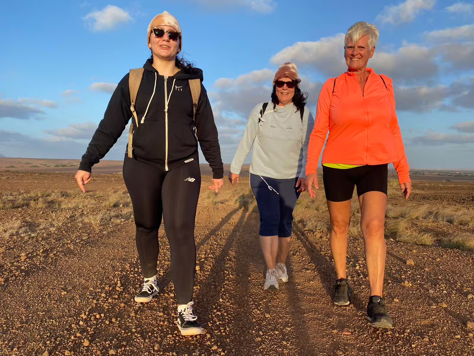 Hikers walking the Mount Lion trail at golden hour, guided sunset trekking experience with coastal views