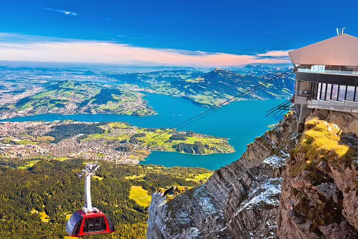 Breathtaking view from Mount Pilatus overlooking Lake Lucerne with a cable car station on the cliffside.