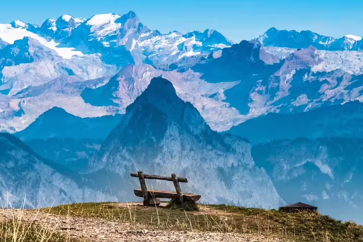 Scenic view from Mount Rigi showcasing panoramic Swiss Alps and a rustic bench perfect for relaxation.