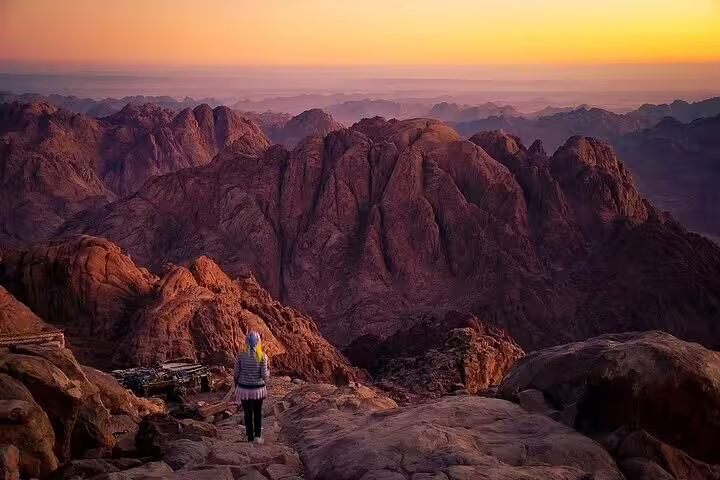 Sunrise over Mount Sinai peaks, traveler on trail during private climb and St Catherine Monastery tour