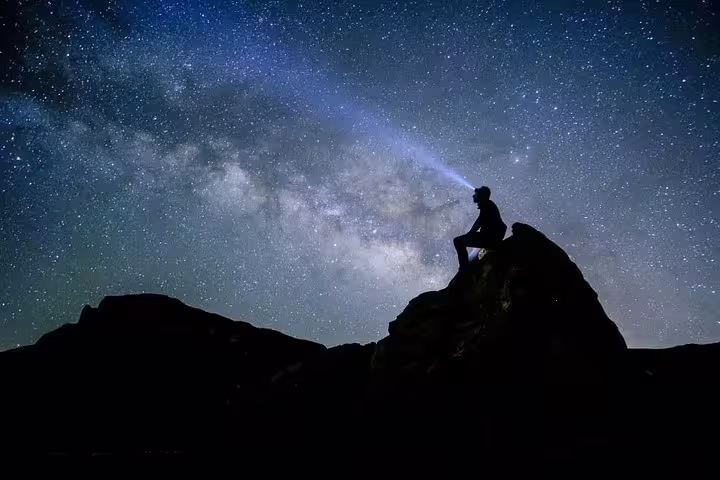 Silhouette of a person stargazing atop Mount Teide under a starry sky, ideal for a memorable night tour experience.