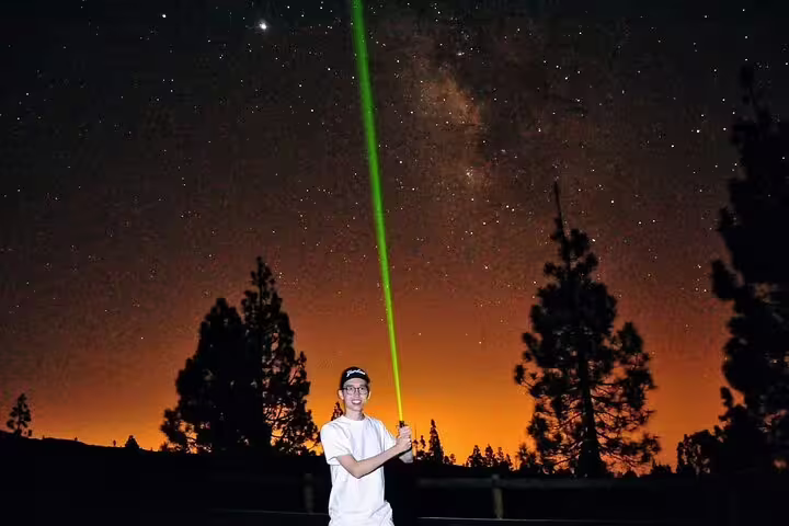 Man using a green laser under a starry sky at Mount Teide, highlighting the amazing stargazing tour with dinner.