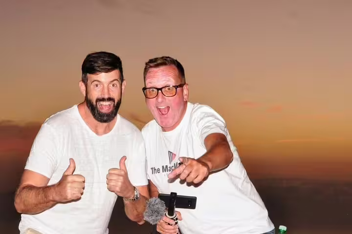 Two joyful tourists giving thumbs up during a vibrant sunset at Mount Teide, ideal for stargazing tours.