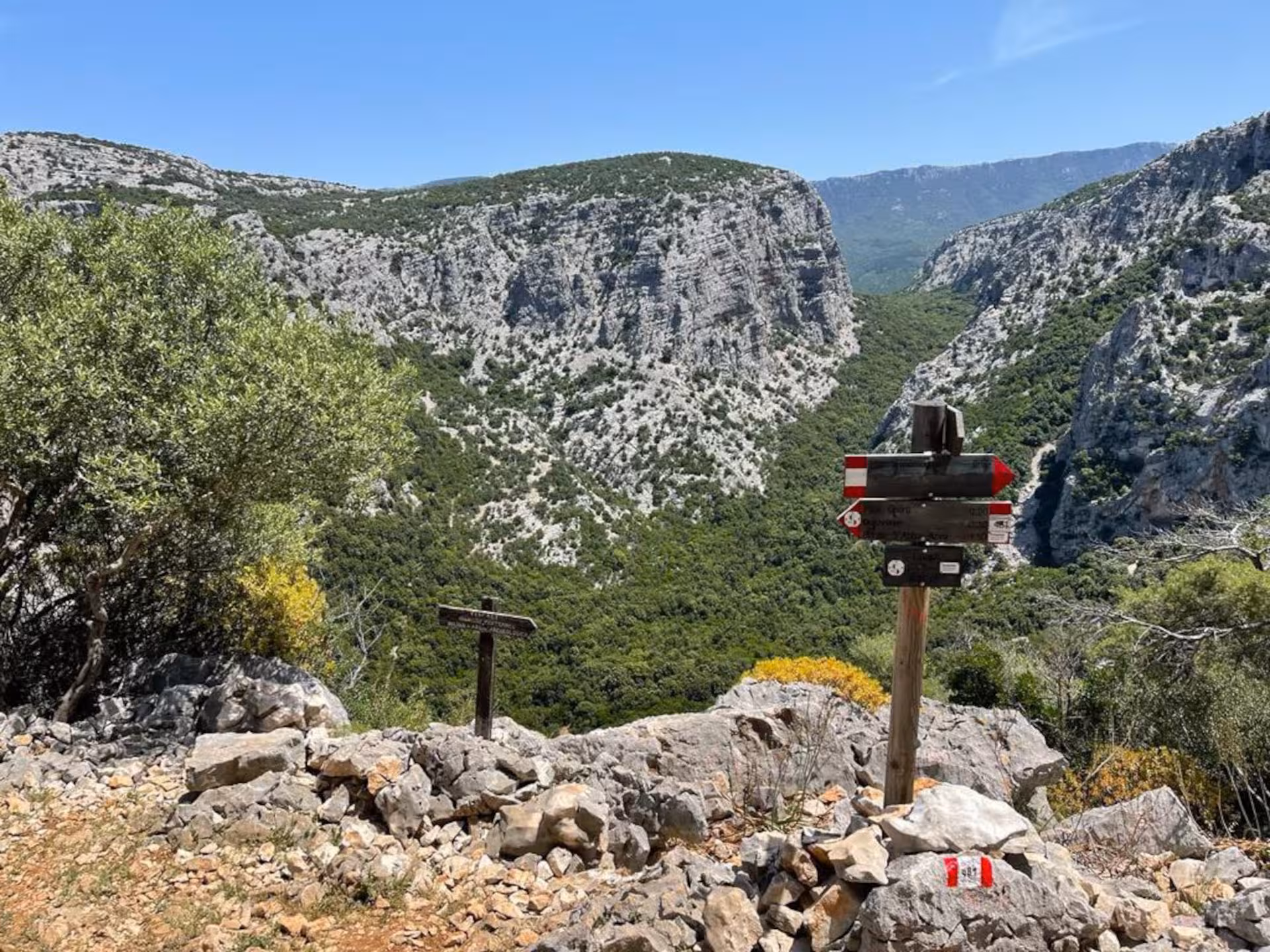 Scenic view of rugged mountains and trekking signs on the trail to Mount Tiscali from Oliena, ideal for hikers.