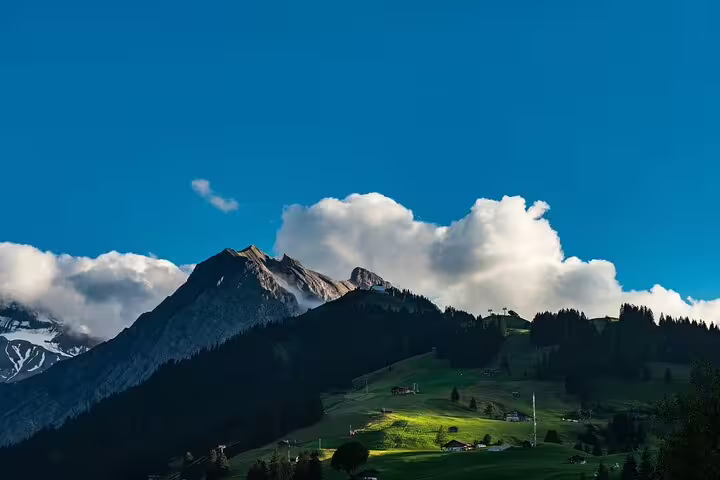 Green alpine meadows and snow-capped Mount Titlis peaks under blue sky near Lucerne Switzerland