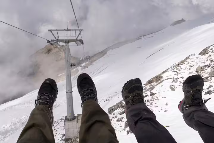 Adventurous cable car ride over snowy landscapes with hikers' feet dangling at Mount Titlis.