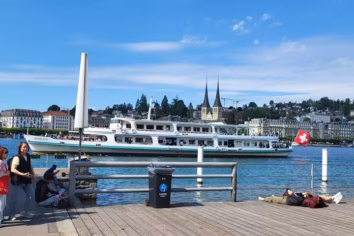 Scenic view of a boat on Lake Lucerne with historic architecture and Swiss flag, ideal for Mount Titlis and Luzern tour.