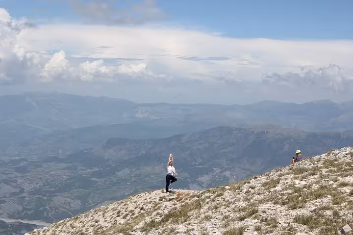 Traveler striking a yoga pose on the scenic summit of Mount Tomorr, offering panoramic views of the Albanian landscape.