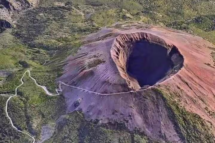 Aerial view of Mount Vesuvius crater and hiking trail through lush slopes on a full-day Private Tour Positano Pompei Vesuvio