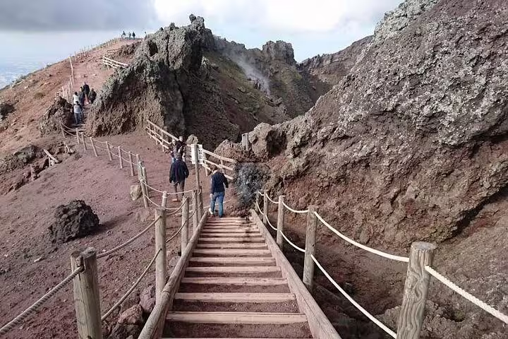 Visitors walking wooden steps along the Mount Vesuvius crater rim on guided private tour from Pompeii, Herculaneum and winery