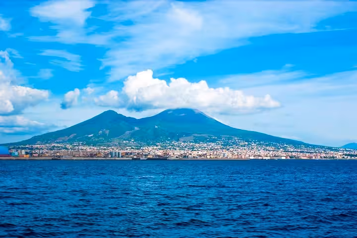 Scenic view of Mount Vesuvius overlooking the vibrant city of Naples and the blue waters of the Bay of Naples.
