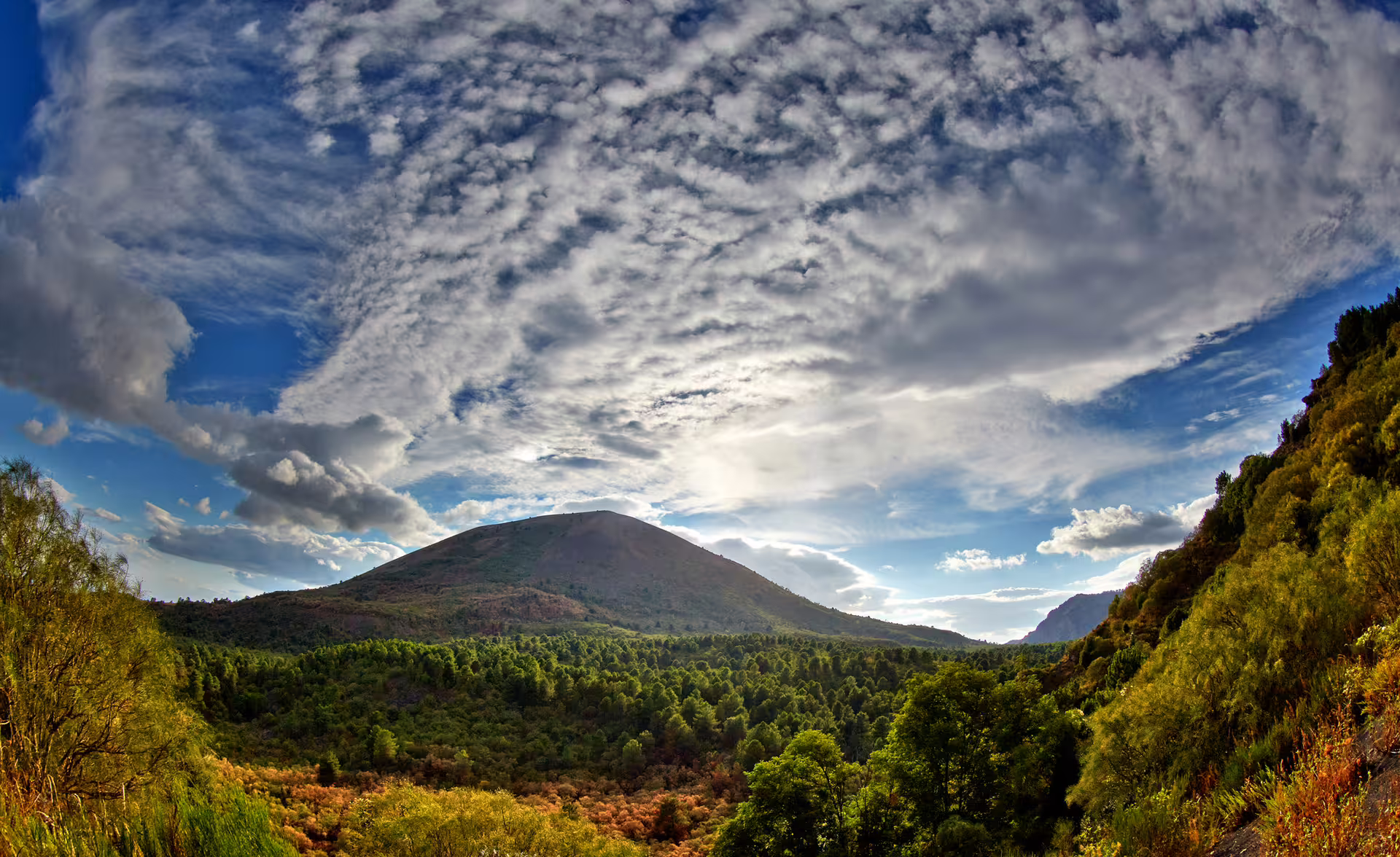 Panoramic view of Mount Vesuvius landscape from Naples group tour, dramatic clouds over green slopes