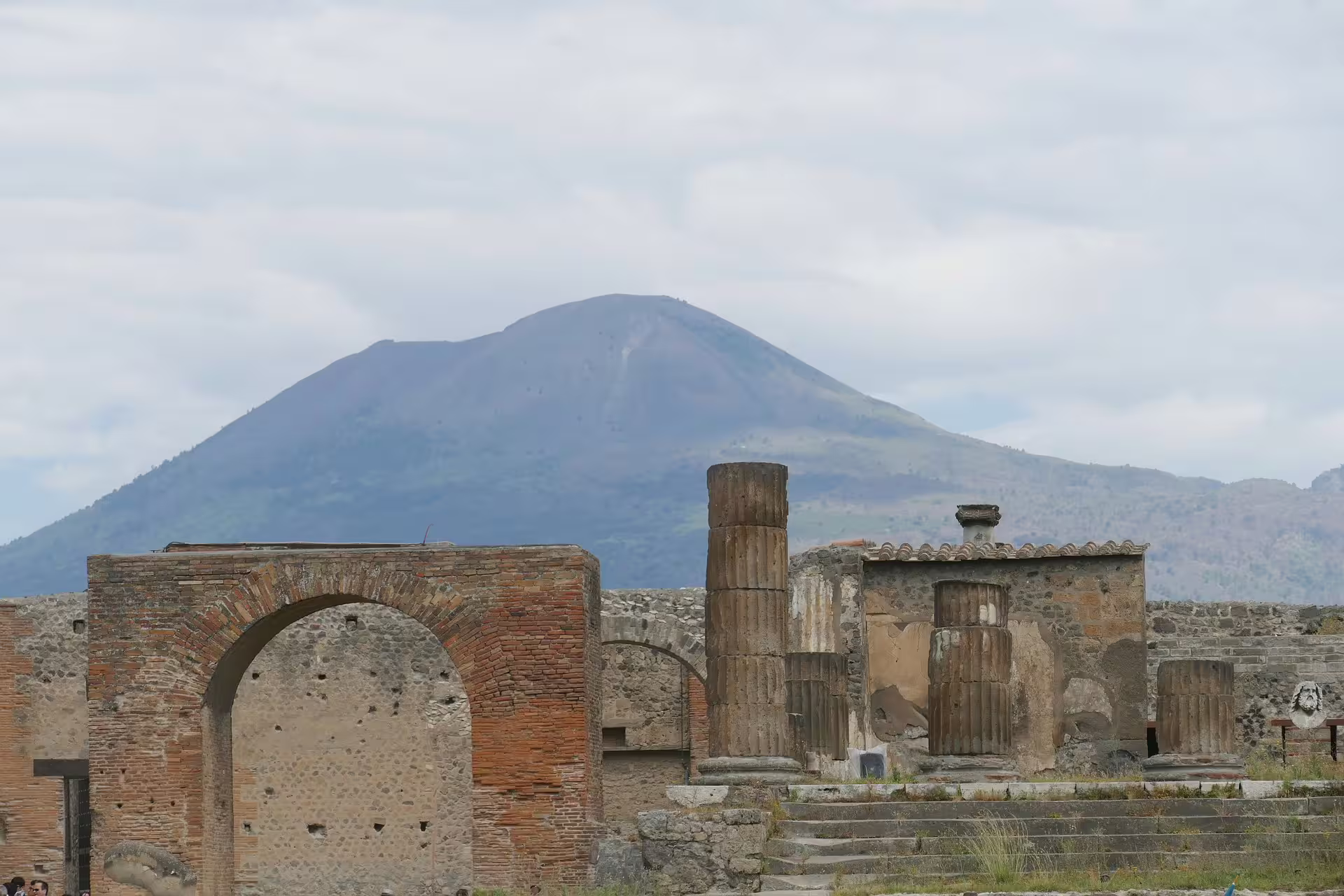 View of Mount Vesuvius behind Pompeii forum ruins and columns on a guided small group archaeological wine tasting tour