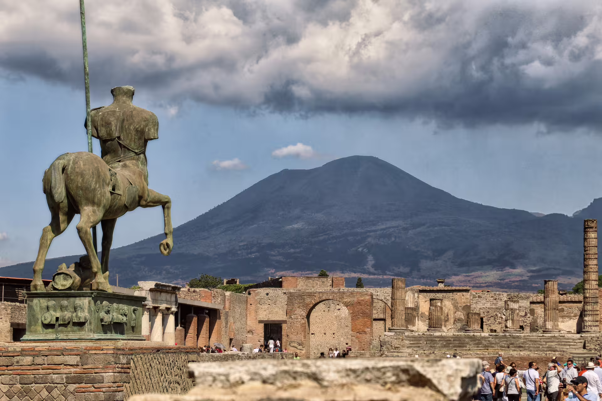 Mount Vesuvius behind Pompeii ruins and equestrian statue, Naples group tour to Pompeii and Herculaneum