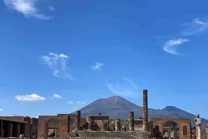Majestic Mount Vesuvius towering over the well-preserved ruins of Pompeii on a bright sunny day, ideal for cultural exploration.