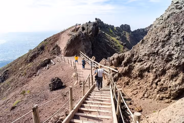 Tourists exploring the wooden pathways of Mount Vesuvius, offering stunning views and adventurous hiking routes.