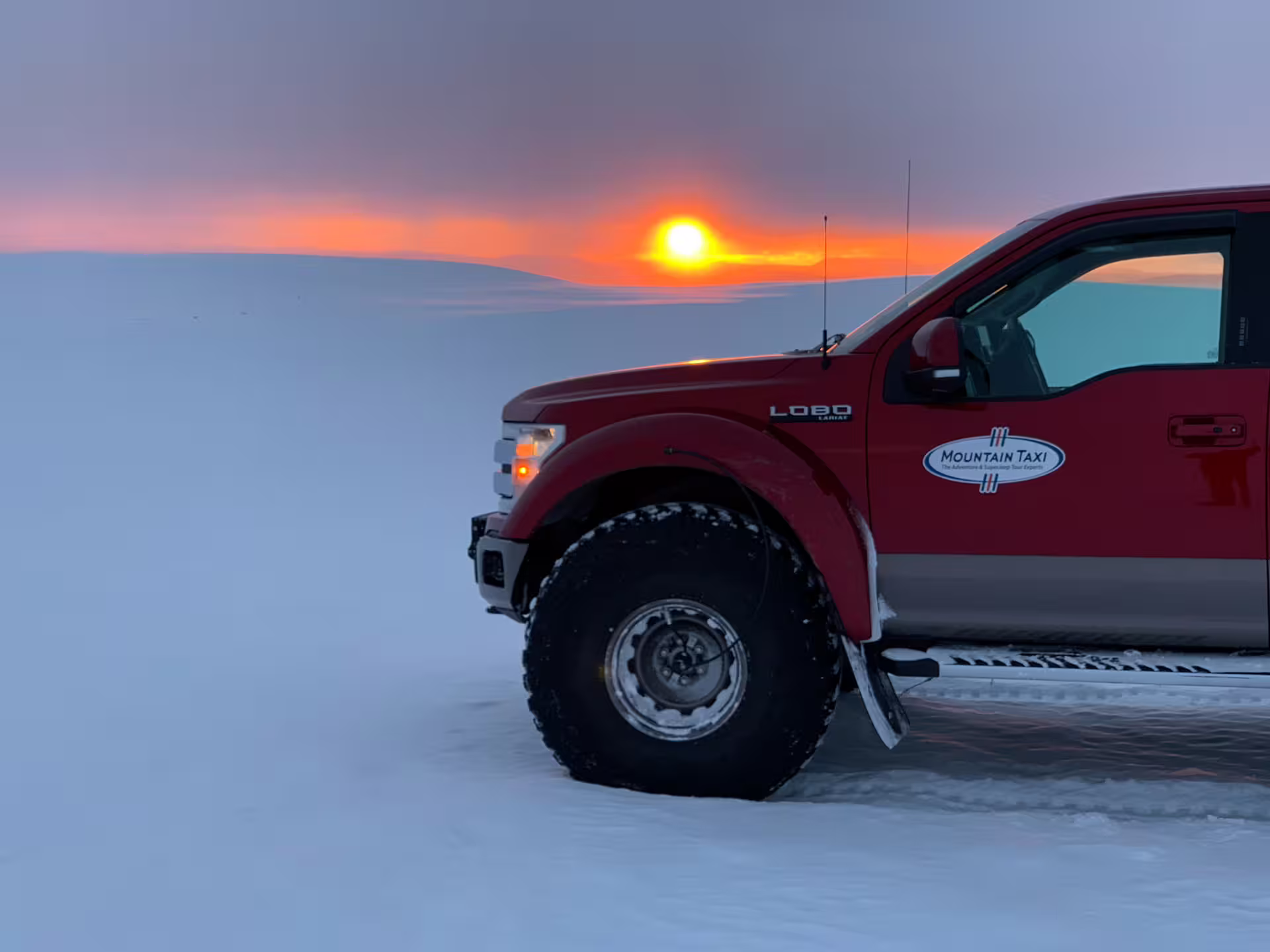 Red Mountain Taxi truck on Langjokull glacier snowfield at sunset in Iceland