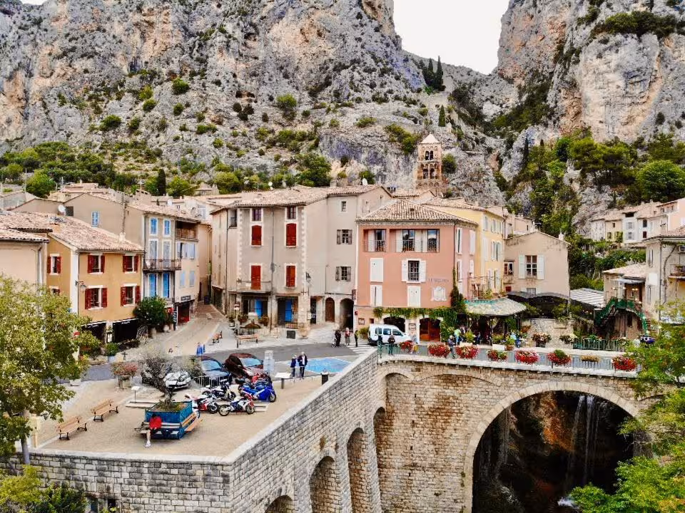 Moustiers-Sainte-Marie village with stone bridge, colorful facades, and dramatic limestone cliffs in Provence, France