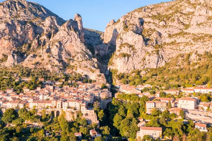 Aerial view of Moustiers-Sainte-Marie village nestled between dramatic limestone cliffs in Verdon region, France