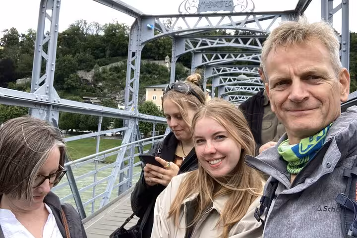 Group of tourists smiling on the Mozartsteg bridge in Salzburg Old Town during a walking tour