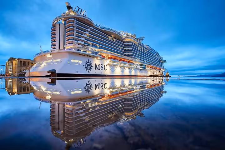 MSC cruise ship illuminated at dusk reflecting on calm water at Villefranche port