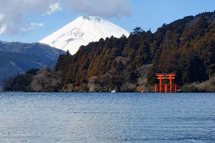 Majestic view of Mt. Fuji behind Lake Ashi and a red torii gate, highlighting the natural beauty of Hakone.