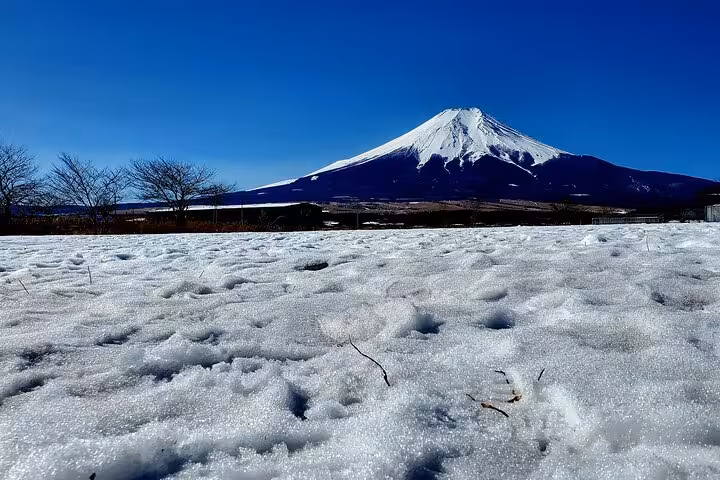 Snow-covered landscape with a stunning view of Mt. Fuji under a clear blue sky in Hakone, Japan.