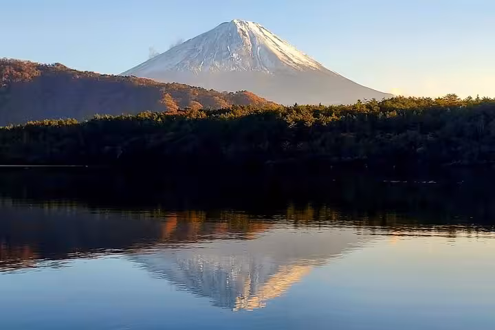 Tranquil reflection of Mt. Fuji on a calm lake at sunrise, highlighting the beauty of a Hakone private tour.
