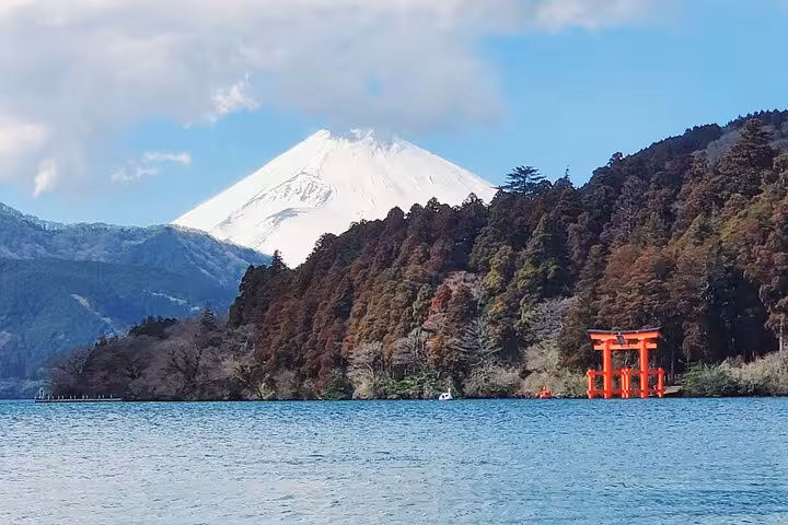 Stunning view of snow-capped Mt Fuji rising above Lake Ashi with red torii gate on Hakone guided tour