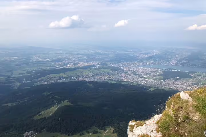 Expansive view from Mt. Pilatus showcasing the verdant Swiss landscape and distant Lake Lucerne, enhancing the tour's allure.