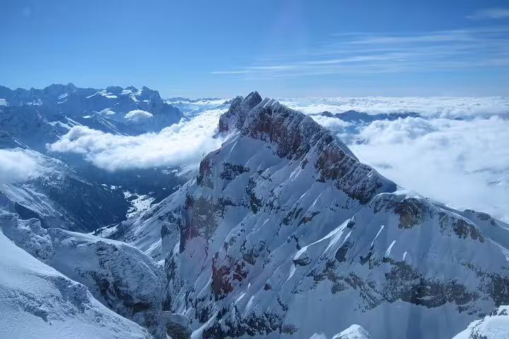 Breathtaking snowy peaks of Mt. Titlis surrounded by clouds, offering stunning alpine views and adventure opportunities.