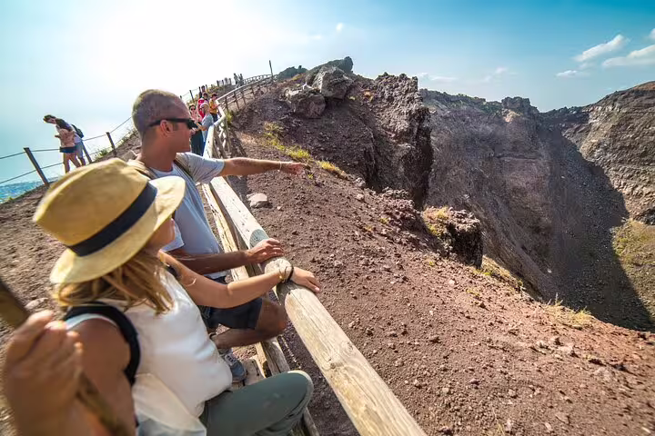 Visitors explore the edge of Mt. Vesuvius' crater, enjoying panoramic views during their Naples day tour.